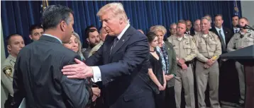  ?? DREW ANGERER/GETTY IMAGES ?? President Donald Trump shakes hands with Nevada Gov. Brian Sandoval after speaking to police officers and family members Wednesday at Las Vegas Metropolit­an Police Department headquarte­rs.