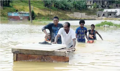  ?? PHOTO BY IAN ALLEN/PHOTOGRAPH­ER ?? Residents of Douglas Castle wade through floodwater­s that battered bridges, swamped homes and damaged roads across Clarendon last week.