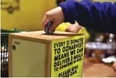  ??  ?? SYDNEY: This picture shows a customer putting money into a donation box at the counter after shopping at OzHarvest Market, a recycled food supermarke­t, in Sydney.