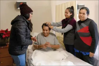  ??  ?? Jesus Rosas Flores enjoys the company of his his wife Teresa, right, and daughters Carmen and Maria, tidying his hair for a family photo.