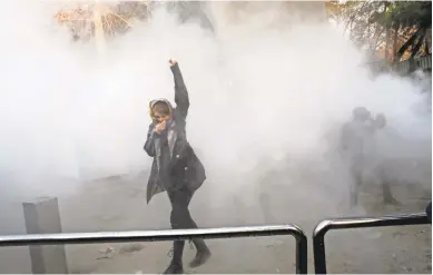  ?? PHOTO VIA AP ?? Tehran University students try to stand their ground against riot police firing smoke grenades and tear gas over the weekend as Iran faced its largest anti-government protests since the disputed presidenti­al election in 2009.