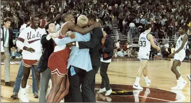  ?? Photo courtesy of UALR ?? UALR players and coaches celebrate after defeating third-seeded Notre Dame in the first round of the 1986 NCAA Tournament in Minneapoli­s. The victory was UALR’s only tournament victory and made the Trojans one of two 14 seeds at the time to make it to...