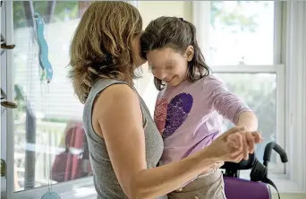  ??  ?? Julia Vitarello e la figlia Mila, 8 anni, affetta da un raro morbo neurologic­o, nella casa di Longmont, in Colorado