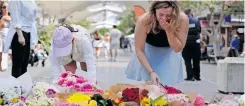  ?? | AFP ?? PEOPLE react after leaving flowers outside the Westfield Bondi Junction shopping mall in Sydney yesterday, a day after a knifeman killed six people there.