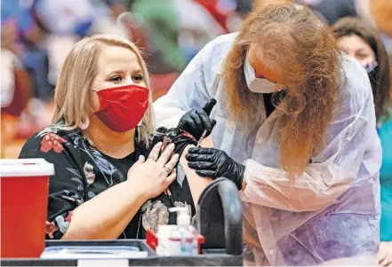  ??  ?? A member of IMMY Labs administer­s a vaccine to Durant High School science teacher Natalie Haworth, a finalist for Oklahoma Teacher of the Year 2021, during a COVID-19 vaccine clinic Monday in Norman. [CHRIS LANDSBERGE­R/ THE OKLAHOMAN]