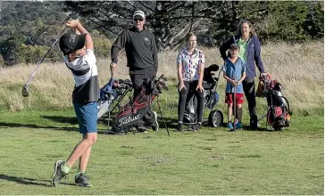  ?? KEVIN STENT/STUFF ?? The Sidford family get a round in whilst staying in their bubble. Nine-year-old Hugo tees off while his family look on, from left: Alastair, Ella,13, Preston,7, and Amy.