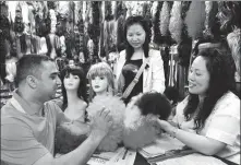  ?? ZHANG JIANCHENG / FOR CHINA DAILY ?? Foreign buyers check out wigs at a trading center in Yiwu, Zhejiang province.