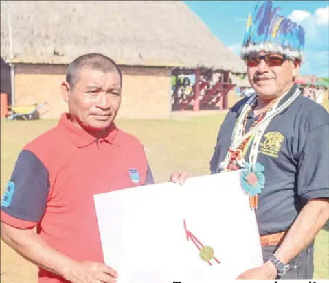  ?? (DPI photo) ?? Minister of Indigenous Peoples’ Affairs, Sydney Allicock (right) presenting the document to Aishalton’s Toshao, Douglas Casimero