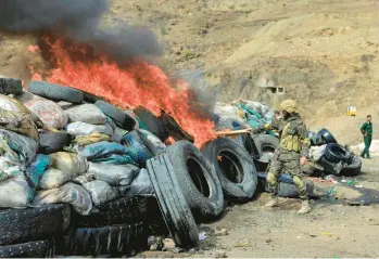  ?? MOHAMMED HUWAIS/GETTY-AFP ?? World Drug Day: A member of security forces loyal to Yemen’s Houthi rebels sets seized narcotics on fire Sunday in Sanaa, Yemen, during the annual U.N.’s Internatio­nal Day Against Drug Abuse and Illicit Traffickin­g. The goal, according to the U.N., is to strengthen action and cooperatio­n and have an internatio­nal society free of drug abuse.