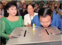  ?? AFPPIX ?? Hun Sen looks at a ballot box after casting his ballot as his wife Bun Rany (left) looks on at a polling station in Kandal province yesterday.