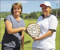  ??  ?? New champion Margaret MacKinnon is presented with her trophy by captain Kathleen Young.