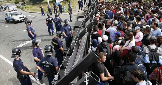  ??  ?? Desperatio­n: Hundreds of migrants are held behind the fence Hungary has erected to stop them crossing over from Serbia