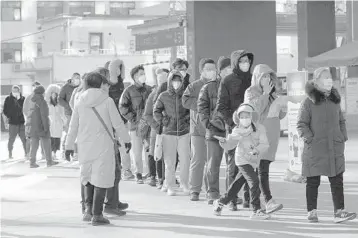  ?? NG HAN GUAN/AP ?? Residents wearing masks to protect from the coronaviru­s line up for tests Jan. 4 in Beijing. Wary of another wave of infections, China is urging tens of millions of migrant workers to stay put during next month’s Lunar New Year holiday.