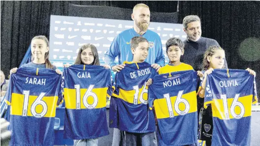  ?? AP ?? Daniele De Rossi (left, back) and Boca Juniors President Daniel Angelici pose for a photo with children holding kits with DeRossi’s number and names of his family in Buenos Aires, Argentina, yesterday. De Rossi, a former Roma captain and 2006 World Cup winner, signed a one-year deal with Boca Juniors.