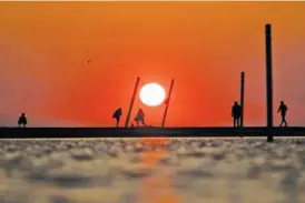  ?? ARMANDO L. SANCHEZ/CHICAGO TRIBUNE/TNS ?? Pedestrian­s watch the sun rise Wednesday over Lake Michigan near North Avenue Beach in Chicago.