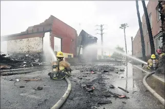  ?? PHOTO BY MILKA SOKO ?? Riverside city Firefighte­rs Connor McClellan and Kyle Sommer extinguish flames at the vacant citrus packing building. The fire erupted about 6:50 a.m. on Thursday.