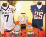  ?? ADOLPHE PIERRE-LOUIS/JOURNAL ?? Nevada’s road white jersey and Arizona’s navy home jersey flank the bowl trophy and player awards, created by artists from Zia Pueblo.