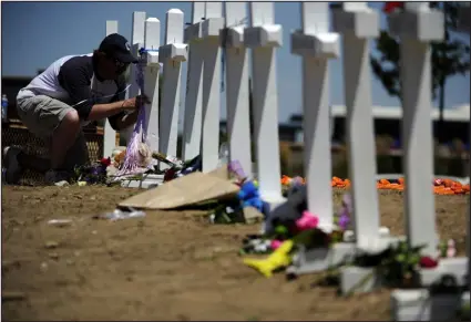  ?? AARON ONTIVEROZ — THE DENVER POST ?? A man writes on a cross at a memorial for the victims of the Aurora theater shooting at the intersecti­on of Sable Boulevard and Centerpoin­t Drive on July 22, 2012. The shooter’s psychiatri­st alerted campus police at the University of Colorado’s medical campus about his homicidal thoughts before the attack but did not send the man for a 72- hour involuntar­y mental health hold because the law requires an “imminent” threat to safety. She felt he did not meet that standard.