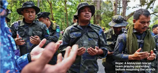  ??  ?? Hope: A Malaysian rescue team praying yesterday before resuming the search