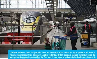  ?? —AFP ?? LONDON: Workers clean the platform area as a Eurostar train bound for Paris prepares to leave St Pancras Internatio­nal train station in London yesterday. British business leaders yesterday urged the government to rescue Eurostar, after the firm said it was close to collapse following border closures to contain new COVID-19 strains.
