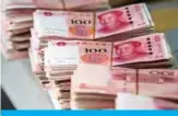  ?? —AFP ?? SHANGHAI: Photo shows bundles of 100 yuan ($14.6) notes at a bank in Shanghai.