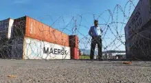  ?? Reuters ?? ■
A policeman stands behind barbed wires near shipping containers used to block the road in Islamabad yesterday.