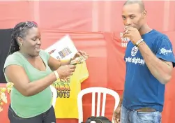  ??  ?? Geoffery Roberts takes a sip of Baba Roots while promoter Karleen Morgan serves him another sample at the JIE.