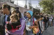  ?? MAURICIO LIMA/NEW YORK TIMES ?? Melissa Guzman (center), from Honduras, waits for food with other migrants outside a recently arranged shelter Saturday in Tijuana, Mexico.