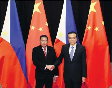  ?? WU HONG / POOL VIA THE ASSOCIATED PRESS ?? Philippine President Rodrigo Duterte, left, shakes hands with Chinese Premier Li Keqiang. The Philippine­s and China have signed a series of trade agreements and promised to continue bilateral talks over the South China Sea.