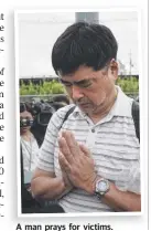  ??  ?? A man prays for victims.