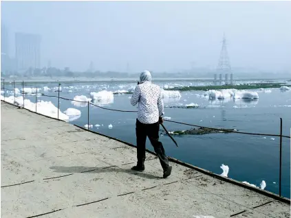  ??  ?? FOAM HOME: A man covers his face to avoid the smells coming from the Yamuna River, Delhi’s most vital water source and India’s most polluted waterway.