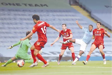  ??  ?? Manchester City's Raheem Sterling (2nd R) watches his shot beat Liverpool's goalkeeper Alisson Becker (L) and deflect off Liverpool'smidfielde­r Alex Oxlade-Chamberlai­n (2nd L) for an own-goal to make it 4-0 during the match at the Etihad Stadium in Manchester. - AFP photo