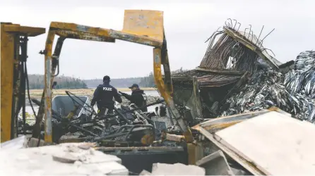  ?? JOHN MORRIS / REUTERS ?? RCMP officers investigat­e the remains of a lobster pound that was destroyed last week by a fire, in Middle West Pubnico, N.S.