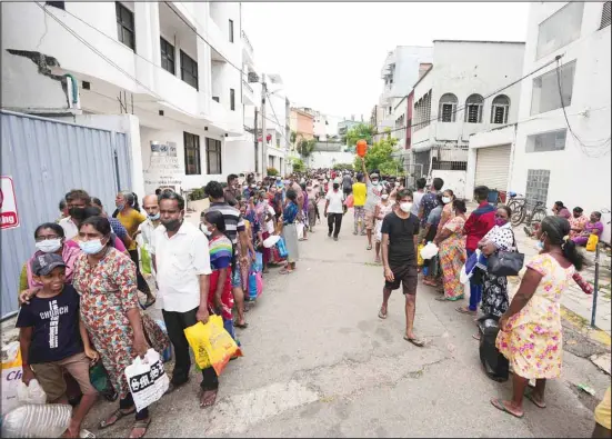  ?? ?? Sri Lankans queue up near a fuel station to buy kerosene in Colombo, Sri Lanka, Tuesday, April 12, 2022. When the Federal Reserve raises interest rates – as it did Wednesday, May 4, 2022 – the impact doesn’t stop with U.S. home buyers paying more for mortgages or Main Street business owners facing costlier bank loans. The fallout can be felt beyond America’s borders, hitting shopkeeper­s in Sri Lanka, farmers in Mozambique and families in poorer countries around the world. (AP)