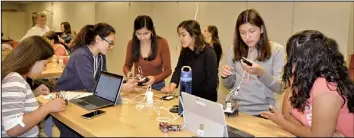  ??  ?? 洛州大暑期班女生們用­電腦和手機設計機器人­編程。（記者丁曙／攝影）