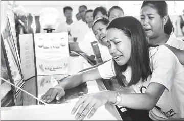  ??  ?? Photo taken on Sept 28 shows Jessel Mae Arzaga, daughter of murdered environmen­tal para-enforcer Ruben Arzaga, weeping as she looks at her father’s body at his wake in the tourist town of El Nido. — AFP photos