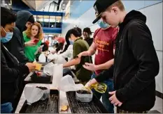  ?? Photos by Paul Buckowski / Times Union ?? Eighth grader Wesley Peden, 13, right, sprays water on seeds he had just placed inside a greenhouse made out of a milk jug at Stephen and Harriet Myers Middle School on March 7. At left, a student holds seeds for peas.