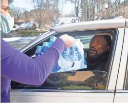  ?? ARIEL COBBERT/THE COMMERCIAL APPEAL ?? A volunteer places a case of drinking water into a resident’s hands at the Pink Palace Museum on Friday. A precaution­ary boil advisory was issued for MLGW customers Thursday.