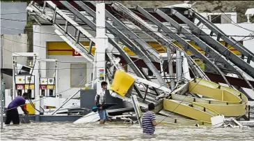  ??  ?? Wrath of
nature: People inspecting a gas station flooded and damaged by the impact of Hurricane Maria in Humacao. — AP