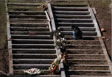  ?? (AP/Esteban Felix) ?? Peruvian migrant Jose Collantes kneels Tuesday at the grave of his wife, Silvia Cano, at the Catholic Cemetery in Santiago, Chile. He said she died from covid-19 complicati­ons.