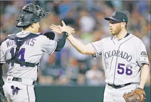  ?? AP PHOTO ?? Colorado Rockies’ Greg Holland, right, is congratula­ted by Tony Wolters after pitching the ninth inning against the Arizona Diamondbac­ks on Saturday in Phoenix. The Rockies won 7-6.