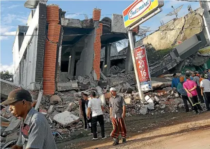  ?? PHOTO: REUTERS ?? People survey the damage after buildings collapsed in a 6.4 magnitude earthquake in the northern province of Aceh, Indonesia, yesterday.