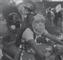  ?? FERNANDO LLANO, THE ASSOCIATED PRESS ?? A protester drives a motorbike wearing a "Monsters Inc." mask through a barricade set up by fellow protesters in Caracas.