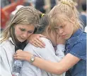  ??  ?? Trista Fogarty, left, Chanelle Plank and Margot Brown, all freshmen at Columbine High in Colorado, embrace at a memorial in 1999. H. DARR BEISER/USA TODAY