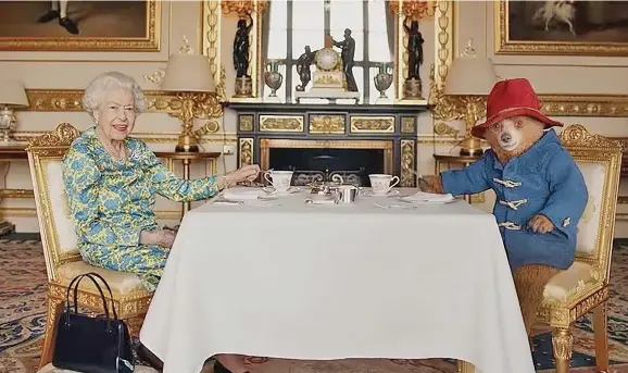  ?? Photo: Daily Mail ?? The Queen has delighted millions of viewers by appearing in a surprise comic sketch with Paddington Bear to kick-start the Jubilee concert. Pictured: Queen Elizabeth II and Paddington Bear having cream tea and a marmalade at Buckingham Palace.