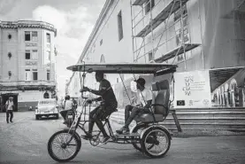  ?? RAMON ESPINOSA/AP ?? A bicycle taxi driver navigates his client past buildings under restoratio­n Saturday in Havana, Cuba. The city will celebrate its 500th anniversar­y Saturday with a jubilee week.