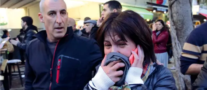  ??  ?? Testimoni Un uomo e una donna, il volto coperto e le lacrime agli occhi, fotografat­i pochi minuti dopo il sanguinoso attentato di ieri a un pub nella centrale via Dizengoff di Tel Aviv, capitale economica di Israele ( Afp)