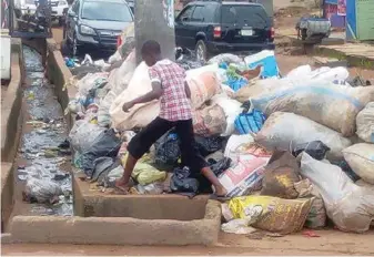  ??  ?? A young resident struggling to pass beside a mountain of refuse