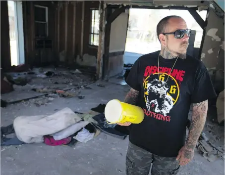  ?? DAX MELMER ?? Andrew Steptoe, owner of a tattoo shop on Wyandotte Street East, picks up used needles strewn about on the ground inside an abandoned building next door to his business. He says addicts “bust through the door and shoot up in here, out of the public eye.”