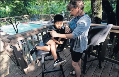  ?? [DAVID J. PHILLIP/THE ASSOCIATED PRESS] ?? Holly Sewell helps Byron talk to his family by phone. Byron now lives with Holly and her husband, Matthew, after spending more than a year in detention facilities with other children who were separated from their migrant parents.